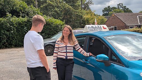 Vikki speaks to a learner driver in front of a car